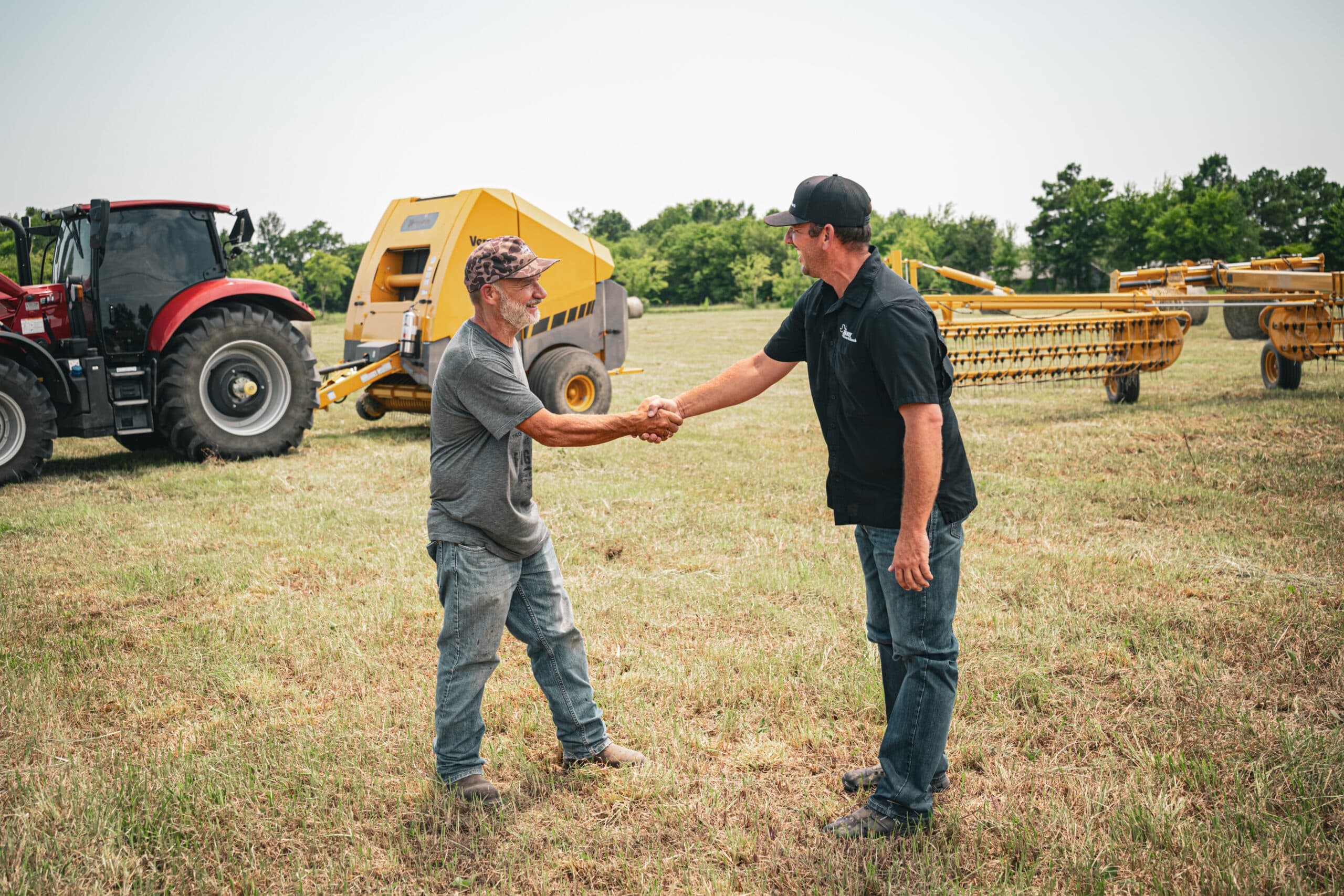 Paris Farm and Ranch employee and customer shaking hands in a hay field.